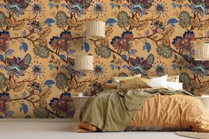 Le papier peint panoramique « Mandil » propose un fond de couleur ocre. Sur la tapisserie, des fleurs stylisées façon mandala s’additionnent dans des arabesques végétales. On dirait un tissu indien. Une variété de petits motifs compose les fleurs du décor mural : traits, gouttes, corolles, points… Les couleurs réveillent la teinte ocre (violet, bleu électrique, bleu turquoise, blanc, rouge, orange, bordeaux…).