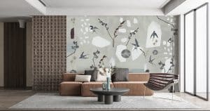 L’hirondelle fait son nid dans la décoration d’intérieur. Papier peint panoramique PAMPA sur un fond qui ressemble à du béton ciré (gris pâle ou bleu cendré selon la version choisie), des hirondelles vont et viennent dans plusieurs sens et positions. Le papier peint imagine un univers entre intérieur et extérieur. On voit sur le décor mural, des vases contenant des fleurs séchées. Les hirondelles volent joyeusement autour. Quelques formes aléatoires, comme si l’on avait cassé de la pierre ou de la faïence, sont disposées ici et là, créant la surprise sur la tapisserie. Le papier peint n’est pas réaliste, pour autant il crée un univers et cela fonctionne. Un air de printemps flotte dans la décoration, dans un style revisité et un brin surréaliste. Les nuances de couleurs et de leurs effets sont discrètes et pourtant attractives. Le décor mural habille le mur avec charme, celui des belles hirondelles. Création © AMELIE NOEL